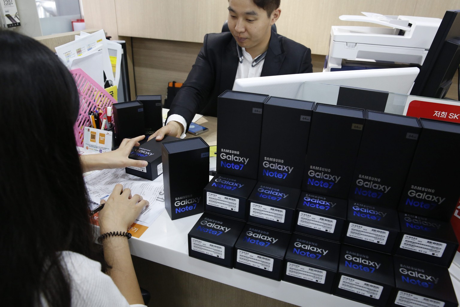 epa05547522 A South Korean customer (L) receives a new Galaxy Note 7 smartphone by an employee of the Samsung Electronics agency, as she visits a store to exchange her smartphone, in Seoul, South Kore ...
