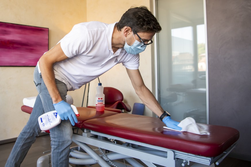 L&#039;osteopathe Boris Hueber, nettoie sa table de massage apres avoir traite un patient en urgence avec de mesures de precautions specifiques dans son cabinet paramedical pendant la crise du Coronav ...