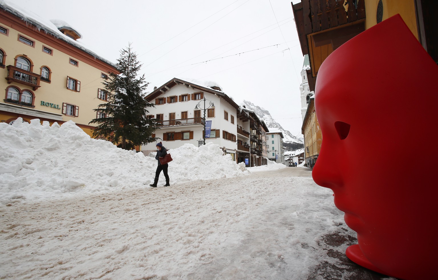 A woman walks in Cortina D&#039;Ampezzo downtown, Italy, Thursday, Jan. 28, 2021. The granite peaks that majestically encircle the northern Italian winter resort of Cortina glimmer with one of the mos ...