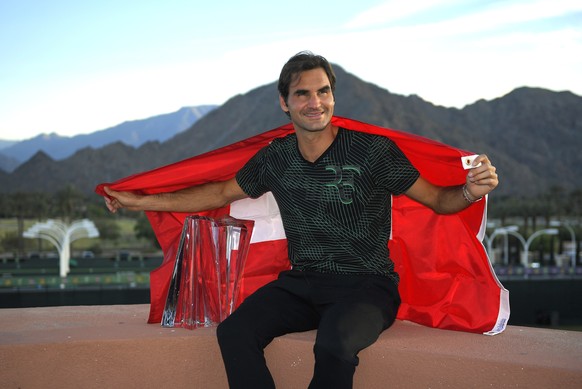 Roger Federer, of Switzerland, poses with his trophy and the Swiss flag after defeating Stan Wawrinka, also of Switzerland, in their final match at the BNP Paribas Open tennis tournament, Sunday, Marc ...