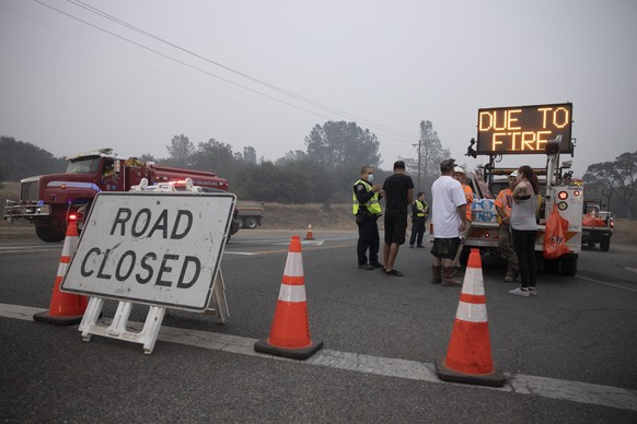 epa08665563 Berry Creek residents speak with authorities at a road block after the Bear fire, part of the North Complex fires, passed through in Berry Creek, California, USA, 12 September 2020. Accord ...