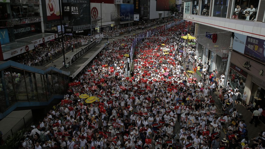 Protesters march on a street as they take part in a rally against the proposed amendments to extradition law in Hong Kong, Sunday, June 9, 2019. The amendments have been widely criticized as eroding t ...