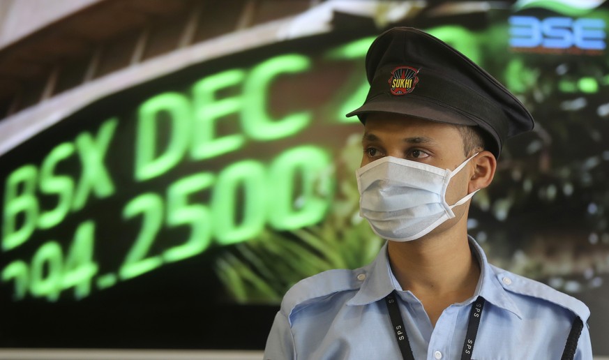 A security guard wearing a mask as a precaution against the new coronavirus stands at the Bombay Stock Exchange (BSE) building in Mumbai, in Mumbai, India, Monday, March 16, 2020. For most people, the ...