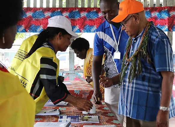 John Momis, right, president of the Autonomous Region of Bougainville, prepares to vote in Buka, Papua New Guinea, Saturday, Nov. 23, 2019, in a historic referendum to decide if they want to become th ...