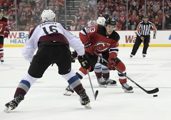 New Jersey Devils center Nico Hischier (13) skates with the puck as Colorado Avalanche defenseman Nikita Zadorov (16) defends during the second period of an NHL hockey game Saturday, Oct. 7, 2017, in  ...