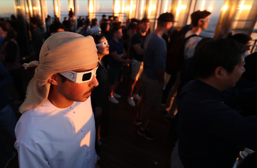 epa08090571 People wearing special glasses watch a partial solar eclipse from the 124th floor of the Burj Khalifa, the world&#039;s tallest building, in Dubai, United Arab Emirates, 26 December 2019.  ...
