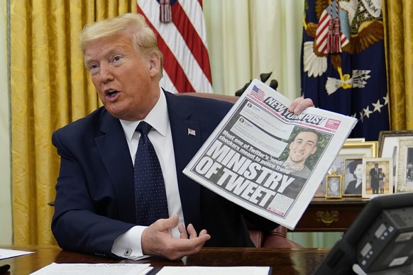 President Donald Trump holds up a copy of the New York Post as speaks before signing an executive order aimed at curbing protections for social media giants, in the Oval Office of the White House, Thu ...