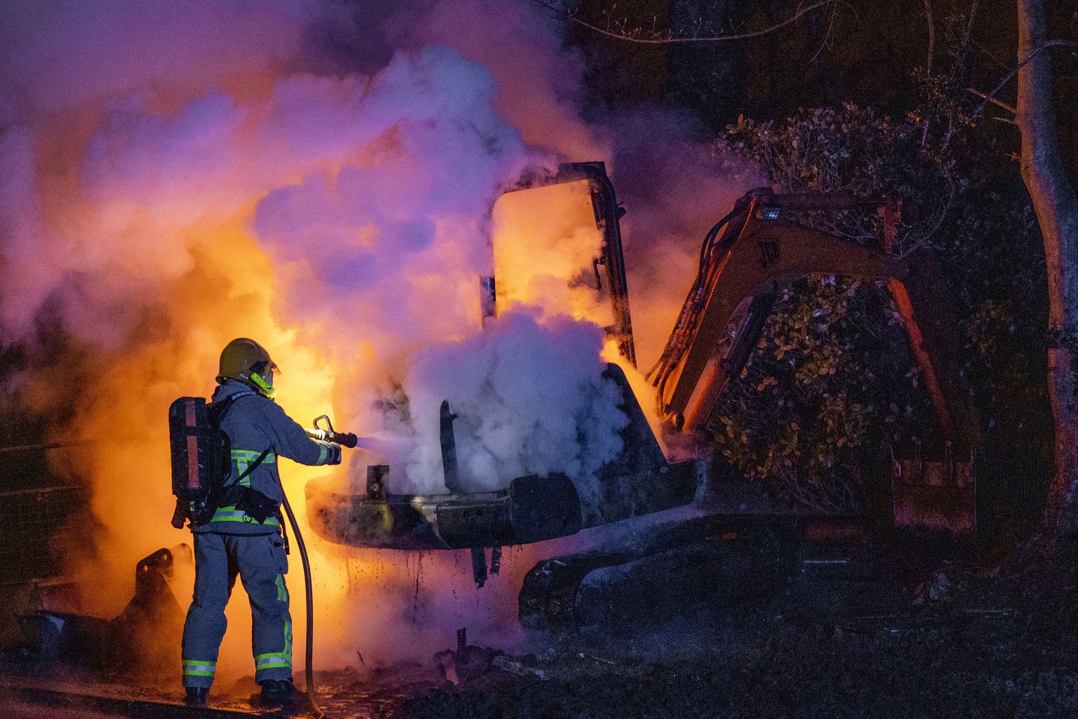 A member of the Northern Ireland Fire and Rescue Service (NIFRS) extinguishes a digger which has been set alight close to the Loyalist Nelson Drive Estate in the Waterside area of Londonderry in North ...