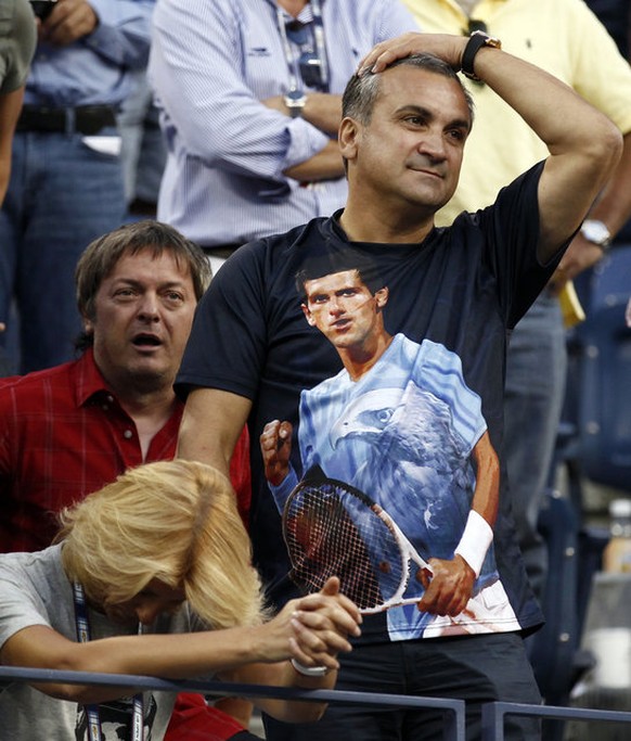 Srdan Djokovic, the father of Novak Djokovic of Serbia, wears a t-shirt with the likeness of his son as he and his wife Dijana (L) watch the match against Roger Federer of Switzerland during the U.S.  ...