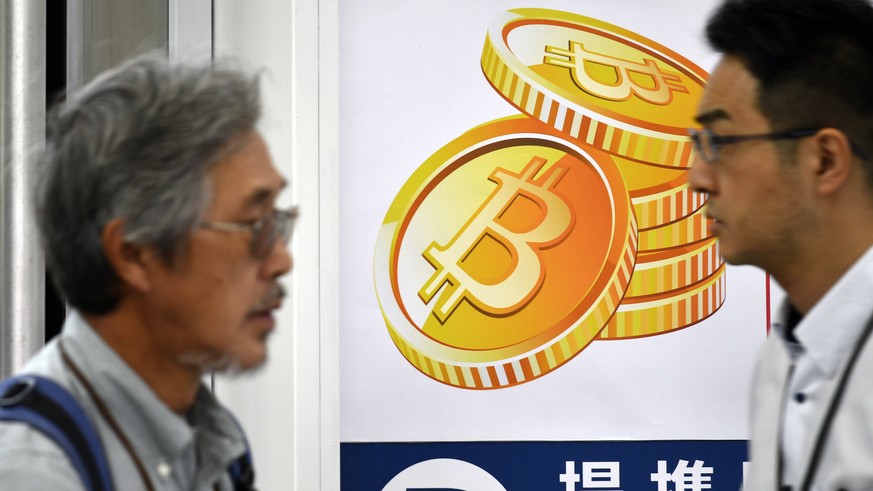 epa06360972 (FILE) - Pedestrians walk past a Bitcoin currency poster at the entrance of a Bic Camera electronics retailers store in central Tokyo, Japan, 01 June 2017 (reissued 01 December 2017). Fina ...