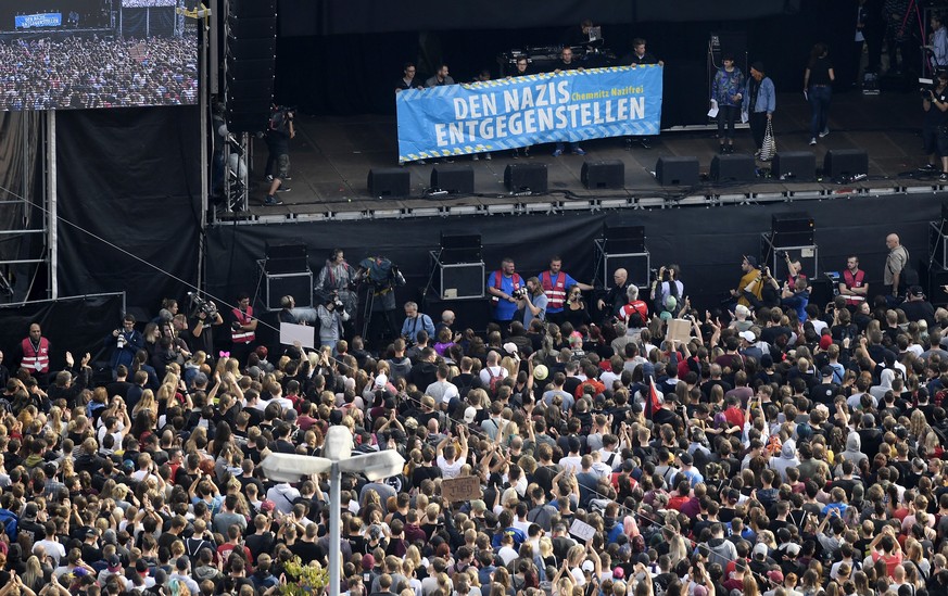 epa06994674 Concert goers stand with their banners in front of a stage in Chemnitz, Germany, 03 September 2018. German music groups give a free concert to support the civil society in Chemnitz. After  ...