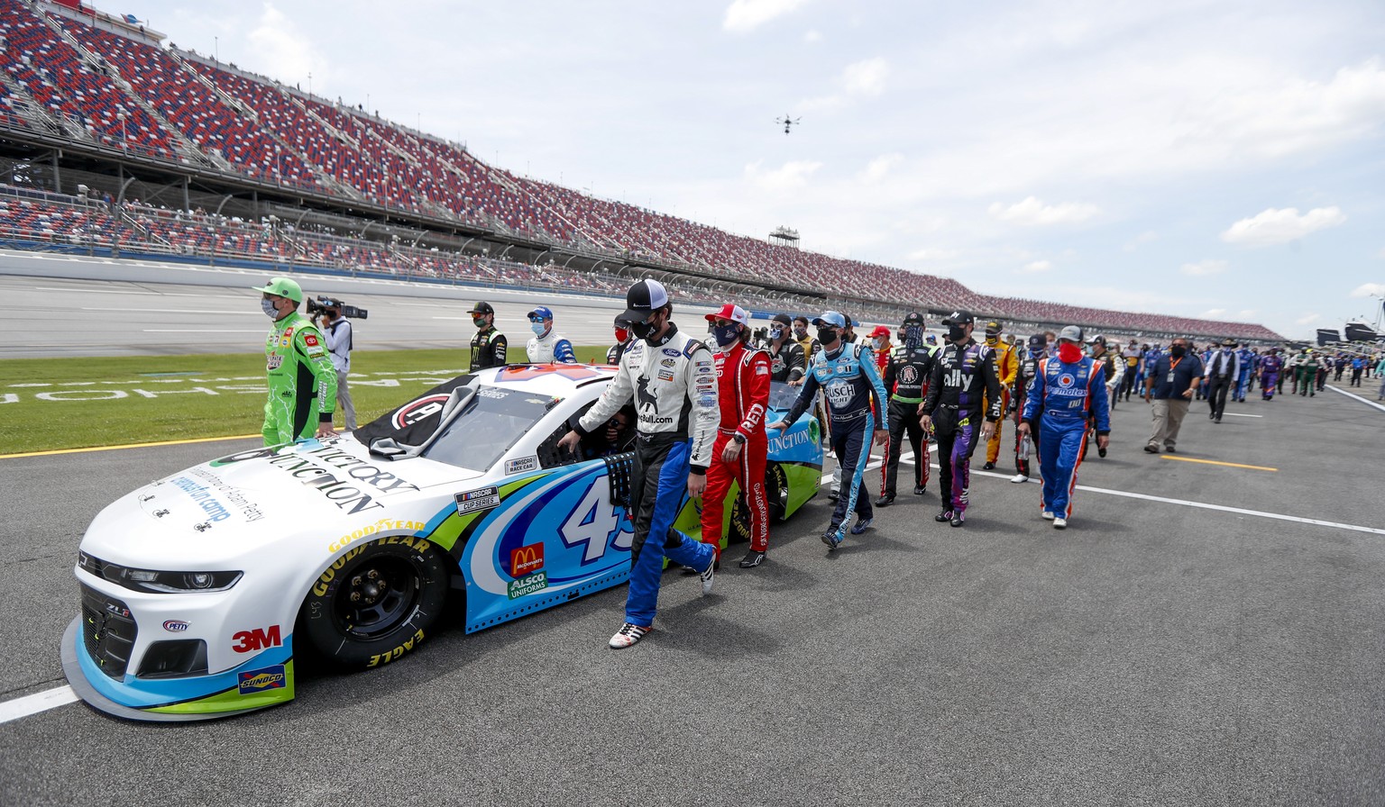 Nascar drivers Kyle Busch, left, and Corey LaJoie, right, join other drivers and crews as they push the car of Bubba Wallace to the front of the field prior to the start of the NASCAR Cup Series auto  ...