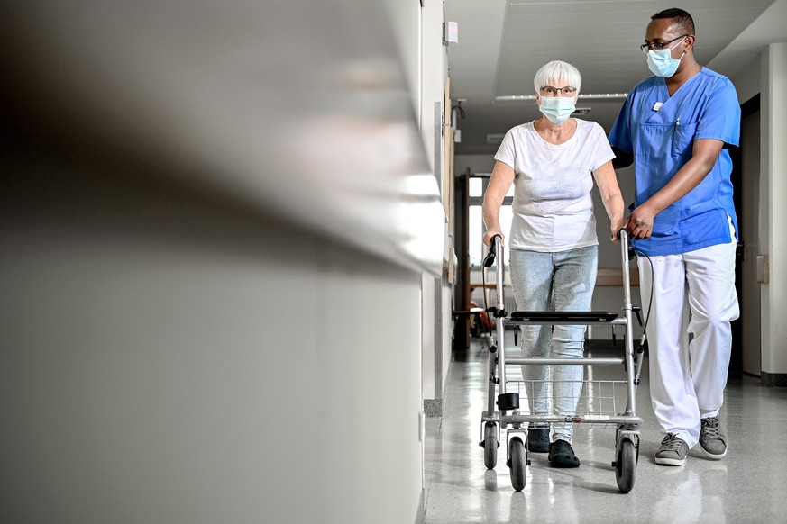 epa08534340 A specially trained carer (R) provides support to an elderly woman on a corridor of a hospital in Schwelm, Germany, 08 July 2020. According to experts, the corona crisis will lead to a sha ...
