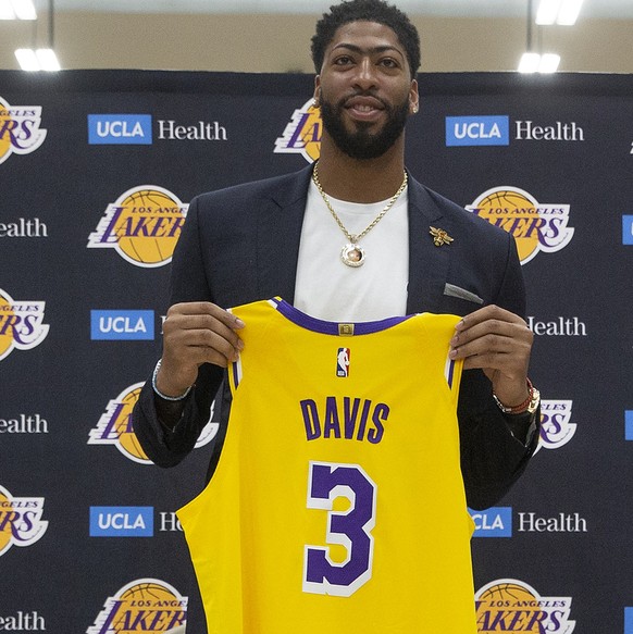 Los Angeles Lakers NBA basketball player Anthony Davis looks down at his number 3 jersey as he is introduced at a news conference at the UCLA Health Training Center in El Segundo, Calif., Saturday, Ju ...