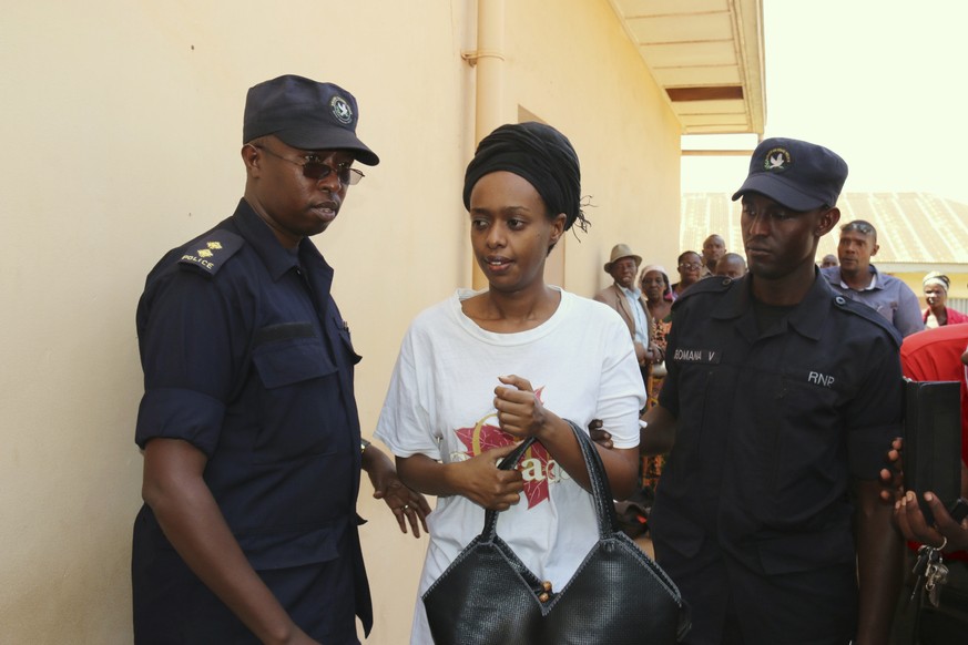 FILE - In this Friday, Oct. 6, 2017 file photo, former Rwanda presidential candidate Diane Rwigara is escorted by policemen to a court where she denied charges of insurrection and forgery that she say ...