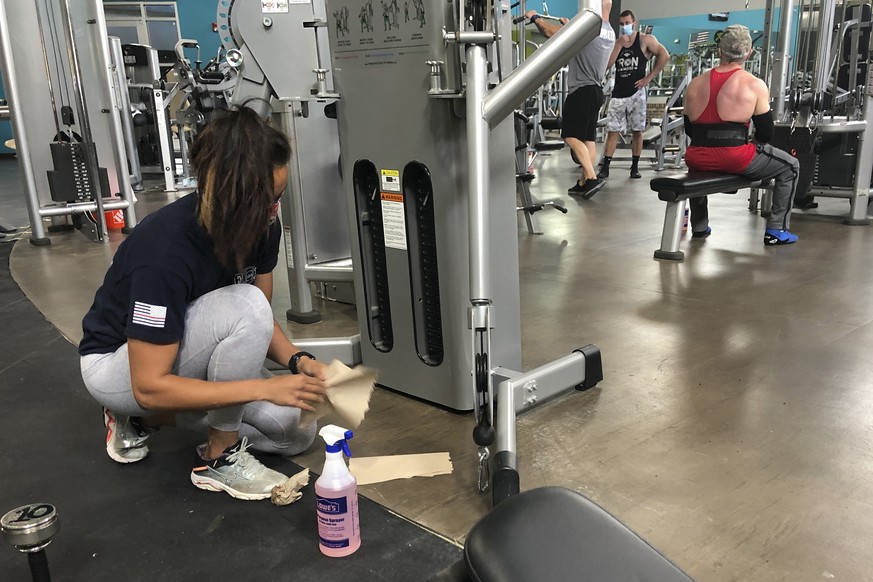 Sterling Henderson, 27, cleans gym equipment at Bodyplex Fitness Adventure on Friday, April 24, 2020, in Grayson, Ga. Gov. Brian Kemp announced this week the resumption of elective medical procedures, ...