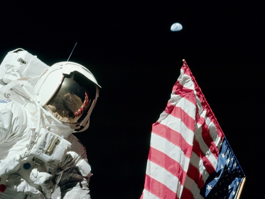 Jack Schmitt von Apollo 17 mit der US-Flagge und der Erde im Hintergrund, 19. Dezember 1972.