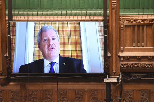 In this handout photo provided by UK Parliament, SNP Westminster leader Ian Blackford asks a a question remotely during Prime Minister&#039;s Questions, as members of parliament observe social distanc ...