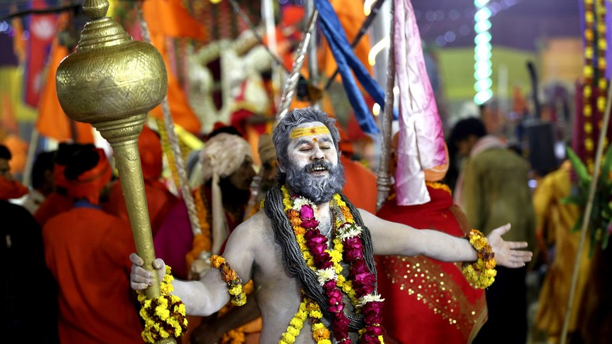 In this Tuesday, Jan.15, 2019, file photo, a Hindu holy man dances holding a mace as he arrives for a ritualistic dip on auspicious Makar Sankranti day during the Kumbh Mela, or pitcher festival in Pr ...