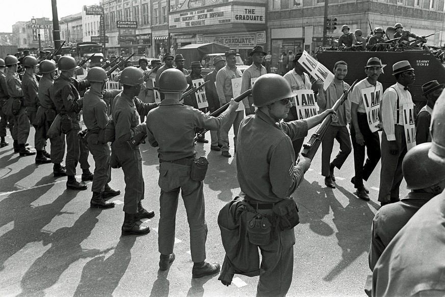 FILE - In this March 29, 1968 file photo, striking sanitation workers march past Tennessee National Guard troops with bayonets during a 20-block march to City Hall, one day after a similar march erupt ...