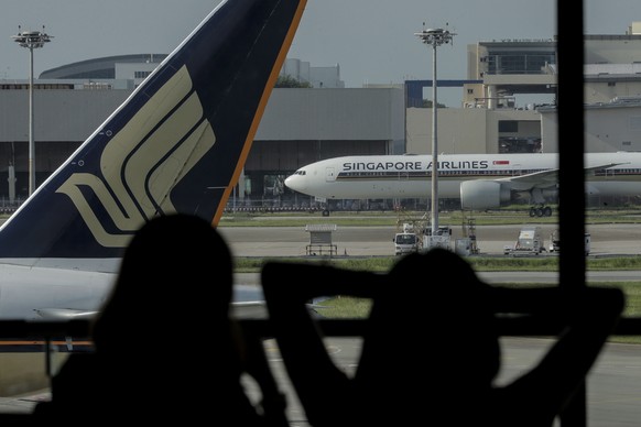 epa08574178 Two women are silhouetted against the Singapore Airlines logo at Changi Airport&#039;s Terminal 1 in Singapore, 30 July 2020. Singapore Airlines has reported a loss of approximately 814.4  ...