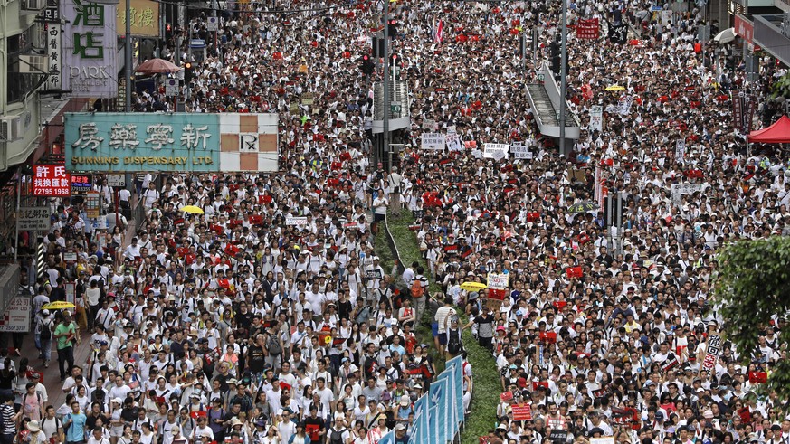 Protesters march along a downtown street to against the proposed amendments to an extradition law in Hong Kong Sunday, June 9, 2019. The amendments have been widely criticized as eroding the semi-auto ...