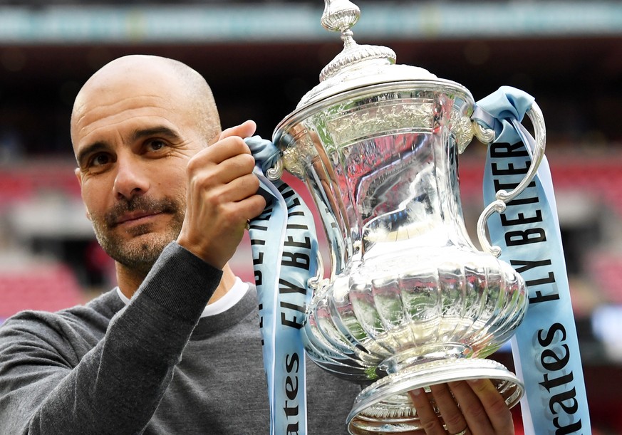 epa07582257 Manchester City manager Pep Guardiola poses with the trophy after the English FA Cup final between Manchester City and Watford at Wembley Stadium in London, Britain, 18 May 2019. Mancheste ...