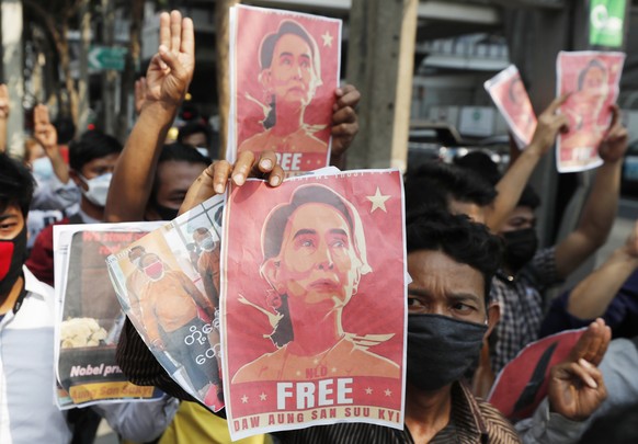 Myanmar nationals living in Thailand hold pictures of Myanmar leader Aung San Suu Kyi gesture with a three-fingers salute of defiance as they protest last week&#039;s military coup in front of the Mya ...