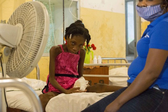 Amazon Annegardine, 11, who is being treated for abnormal blood sugar levels, sits on a bed accompanied by her mother at the Hospital��of��Immaculate Conception, in Les Cayes, Haiti, Wednesday, May 26 ...