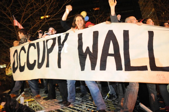 FILE- In this Saturday, Dec. 31, 2011 photo, Occupy Wall Street protesters celebrate in Zuccotti Park in New York, while standing on barricades they removed from around the park. New York City has agr ...