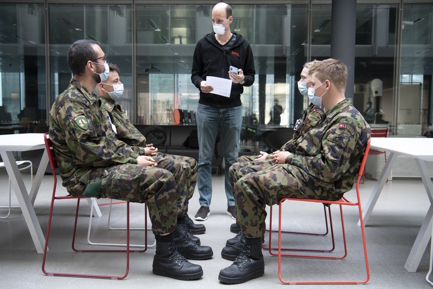 Soldiers of the Swiss army wearing protective face mask and with Android and iOS (Google and Apple) smartphone in the pocket are picturing during a test of a smart phone app using Decentralized Privac ...