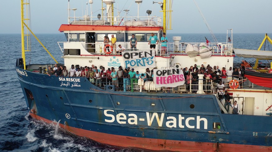 epa07676750 A handout photo made available by Sea-Watch on 27 June 2019 shows migrants holding up banners asking for &#039;Open Ports&#039; and &#039;Open Hears&#039; on board the Sea-Watch 3 vessel,  ...