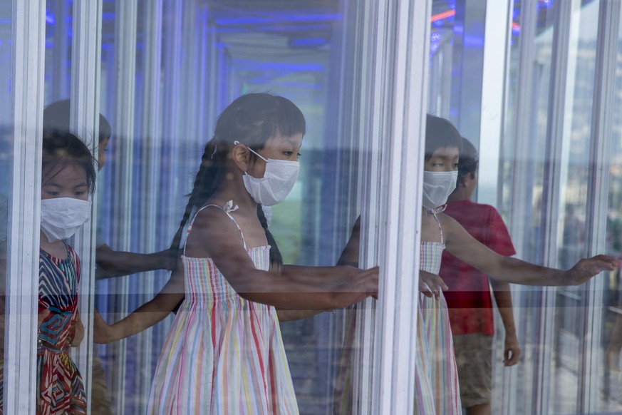 Children wearing as a precaution against the spread of the coronavirus COVID-19 walk in a glass maze, during the Luna Park on the Bank of the Geneva lake, in Geneva, Switzerland, Saturday, August 1, 2 ...