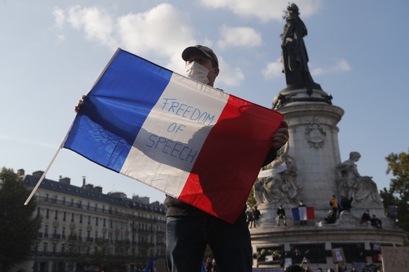 A demonstrator holds a French flag with the slogan &quot;Freedom of Speech&quot; during a demonstration Sunday Oct. 18, 2020 in Paris. Demonstrations around France have been called in support of freed ...