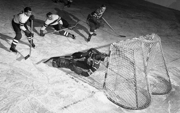 Canadian goalie Ralph Hench sprawls on ice in front of goal as he makes a save in Winter Olympic ice hockey match with German team, Feb. 15, 1952 in Oslo, Norway. Attacking Germans are Xaver Unsinn, l ...