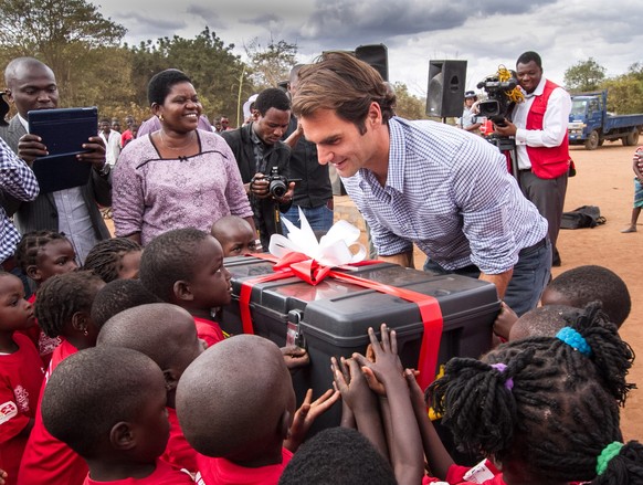 epa04854275 Swiss tennis player Roger Federer provides a box of gifts to school children during the ceremony in Lilongwe, Malawi, 20 July 2015. The Roger Federer Foundation is a community based care f ...