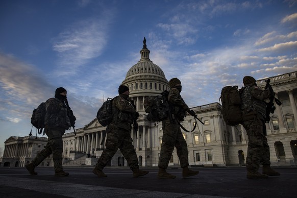 epa08937459 National Guard troops march past the US Capitol building as day breaks in Washington, DC, USA, 14 January 2021. At least twenty thousand troops of the National Guard will be deployed in Wa ...