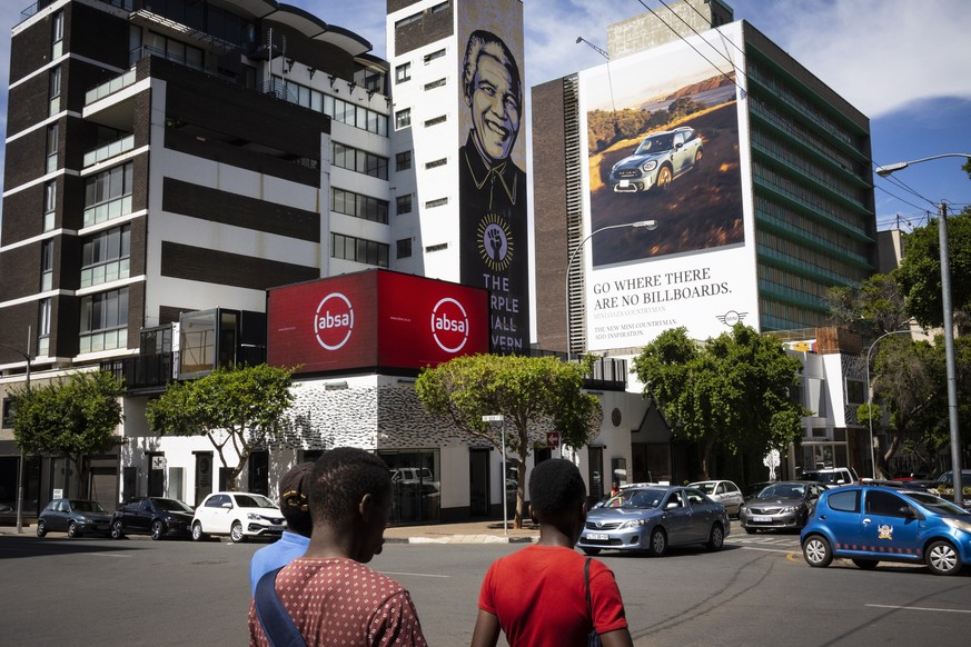 epa08873871 Pedestrians walk past bank and car dealership advertising in downtown Johannesburg, South Africa, 10 December 2020. Data from STATS SA, the national statistical service of South Africa, re ...