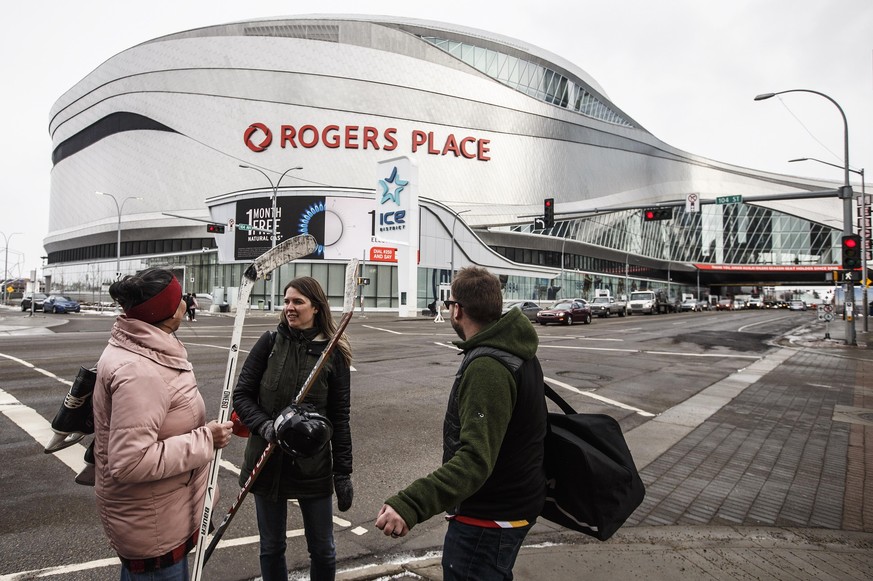 FILE - In this March 12, 2020, file photo, people talk outside Rogers Place, the home ice of the NHL hockey club Edmonton Oilers, in Edmonton, Alberta. Rogers Place is one of the possible locations th ...