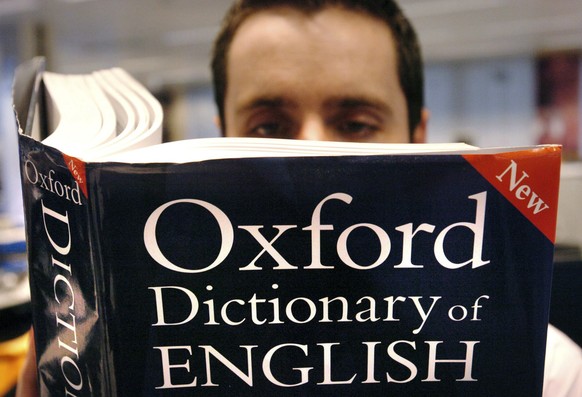 FILE - In this March 14, 2007 file photo, a man reads a copy of the Oxford Dictionary of English. Oxford Dictionaries is recognizing the power of the millennial generation with its 2017 word of the ye ...