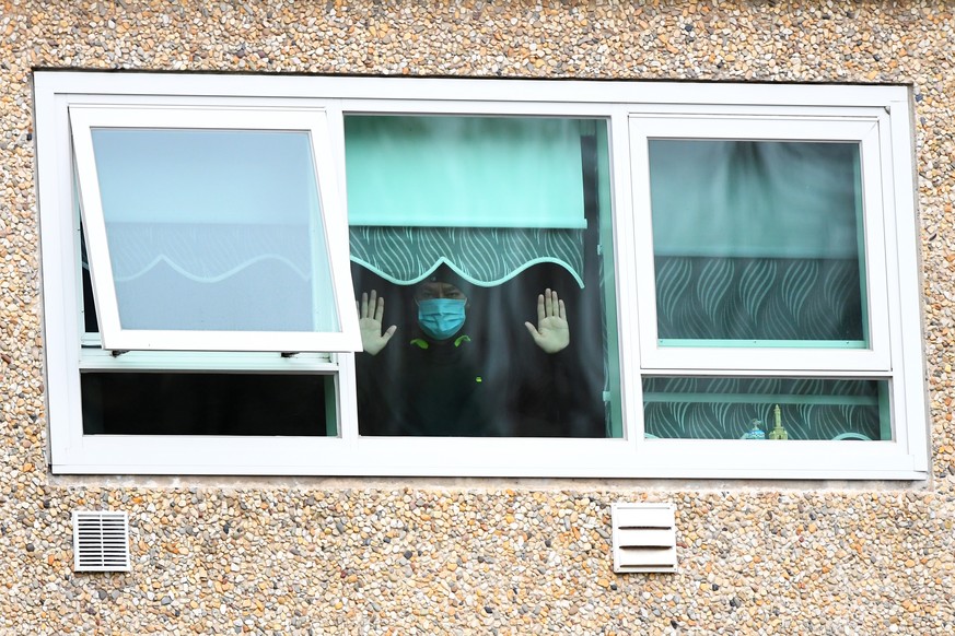 epa08530263 A man gestures from a window inside a unit at the public housing tower under lockdown along Racecourse Road in Melbourne, Australia, 06 July 2020. Victoria?s Premier has ordered the immedi ...