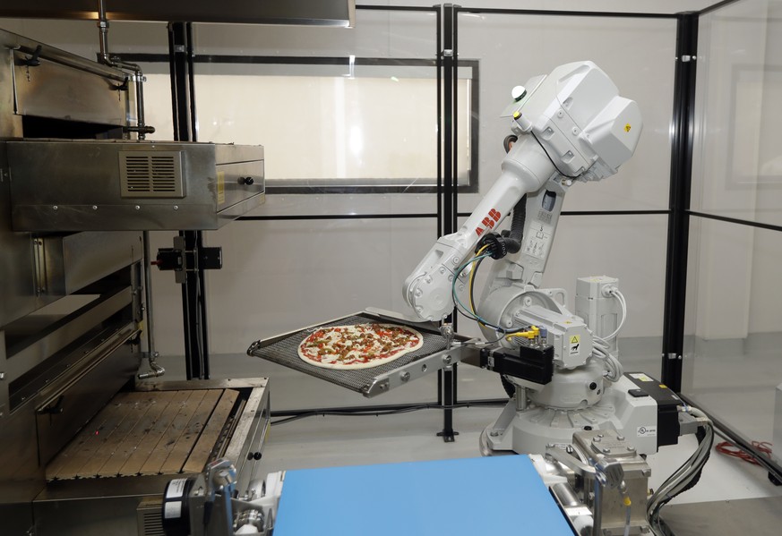 In this Monday, Aug. 29, 2016 photo, a robot places a pizza into an oven at Zume Pizza in Mountain View, Calif. The startup, which began delivery in April, is using intelligent machines to grab a slic ...