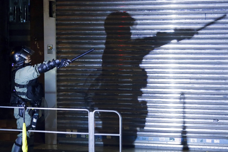 A riot policeman gestures as police disperse the residents and protesters at Sham Shui Po district in Hong Kong, Wednesday, Aug. 7, 2019. Protesters surrounded a Hong Kong police station to demand the ...