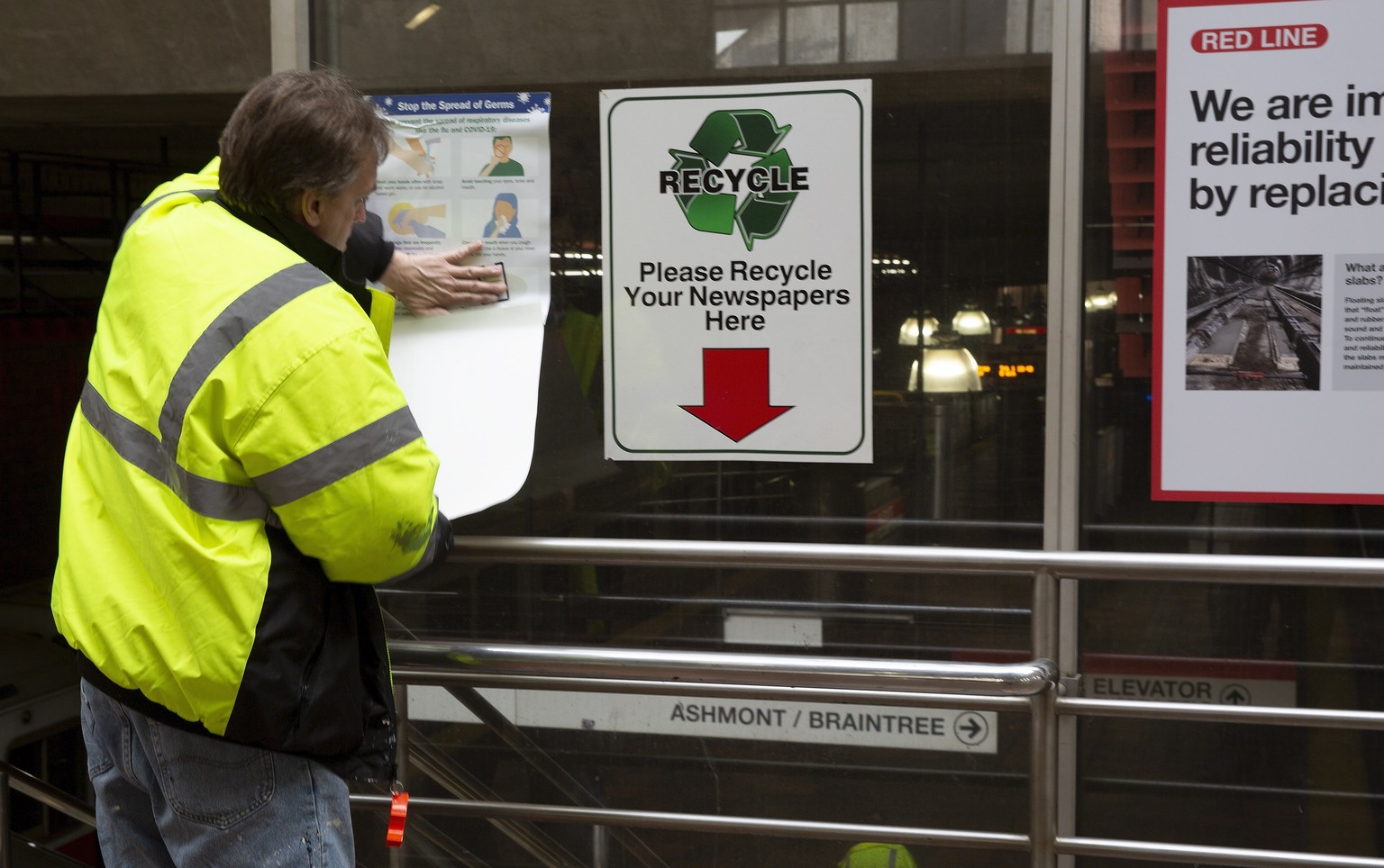 epa08283648 An MBTA (Massachusetts Bay Transit Authority) employee installs signs warning passengers to take precautions in helping to avoid spreading the Corona Virus at the Alewife Train in Cambridg ...