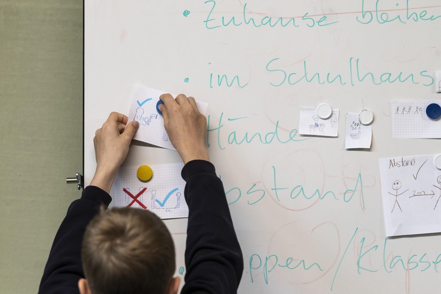 Ein Schueler befestigt Entwurfe fuer Piktogramme zu den hygienischen Verhaltensregeln an der Magnetwand, am Tag der Wiedereroeffnung der Lorraineschule, am Montag, 11. Mai 2020 in Bern. Die Schulen wu ...