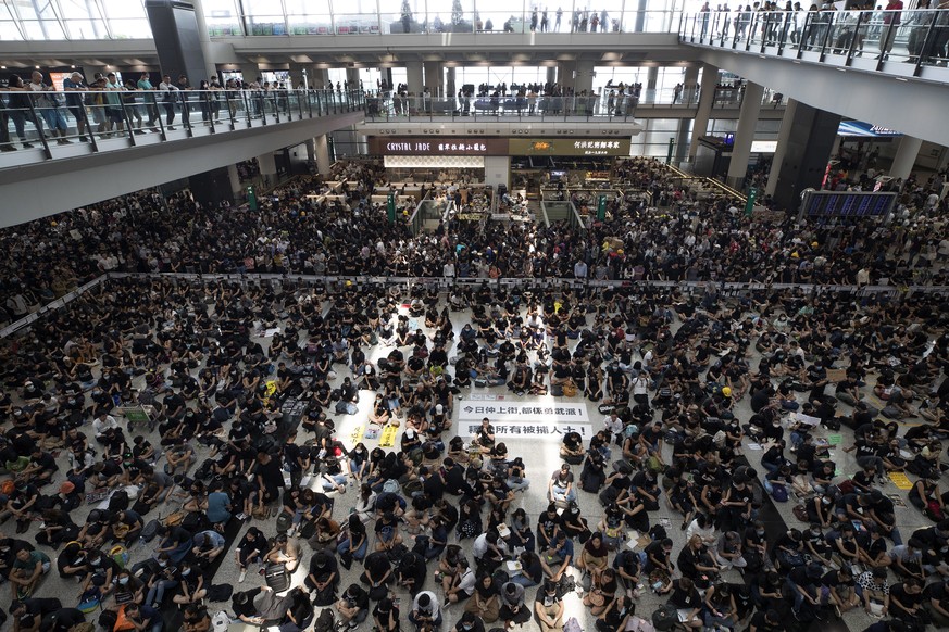 Protesters surround banners that read &quot;Those charge to the street on today is brave!,&quot; center top, and &quot;Release all the detainees!&quot; during a sit-in rally at the arrival hall of the ...
