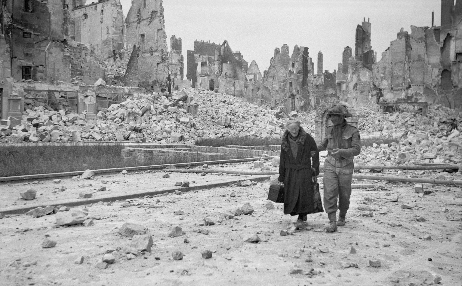 Ein britischer Soldat begleitet eine alte Dame durch Caen, Juni 1944. Die deutschen Verteidiger leisteten unerwartet massiven Widerstand, als die alliierten Truppen nach der Landung in der Normandie v ...