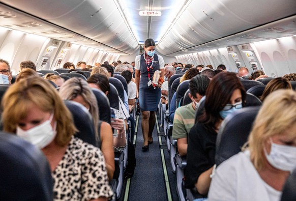 epa08510310 Passengers and a flight attendant with face masks sit in a Corendon Dutch Airlines plane bound for Burgas in Bulgaria, departing from Schiphol Airport, near Amsterdam, The Netherlands, 26  ...