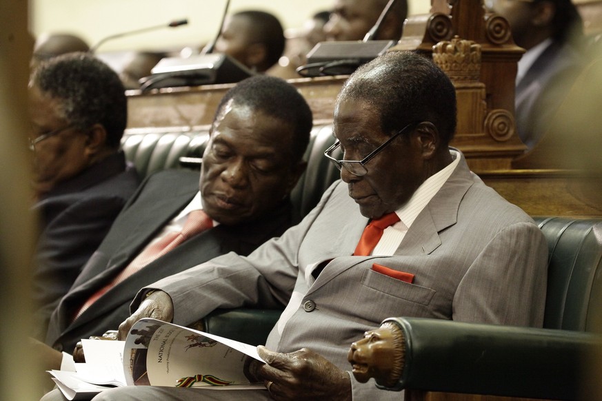 epa06330550 (FILE) - Zimbabwean President Robert Mugabe (R) is flanked by Vice President Emmerson Mnangagwa (L) as he reads a copy of the country&#039;s 2017 National Budget in the house of parliament ...