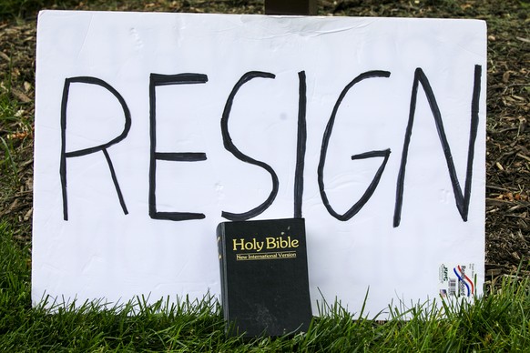 A sign says &quot;resign&quot; as a Bible is propped against it during a protest of the arrival of President Donald Trump to the Saint John Paul II National Shrine, Tuesday, June 2, 2020, in Washingto ...